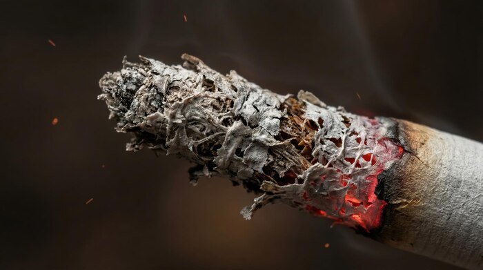 cigarette-tip-smoldering-with-ash-dark-background_342166-19433